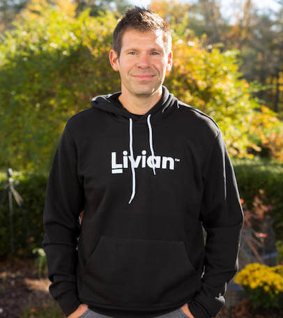 Adam Hergenrother standing outside wearing a black sweatshirt with white text on it that reads 'Livian'.